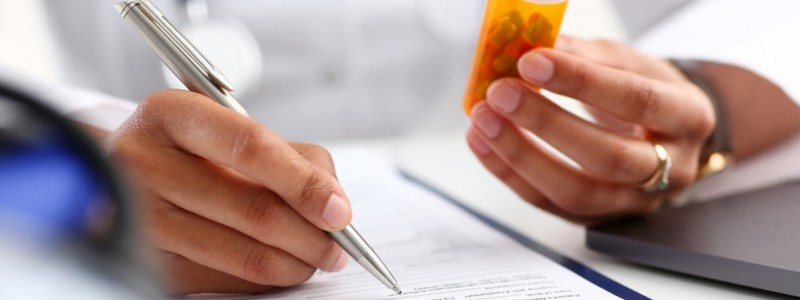 African American lady doctor writing a prescription for pills