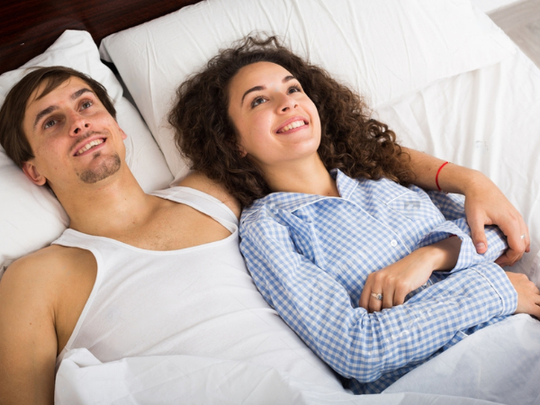 Happy man and woman lying in bed with smile