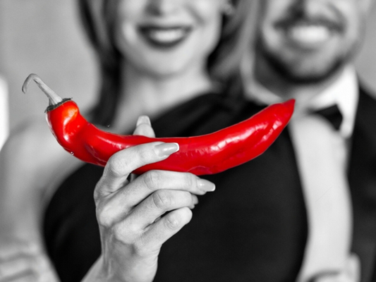 Machismo Plus couple holding a red pepper signifying healthy penile blood flow