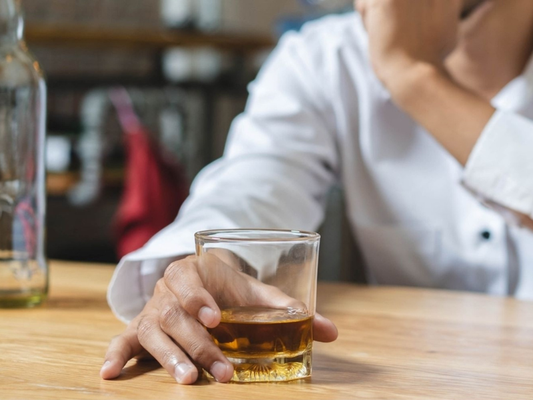 Man holding a glass of alcohol, illustrating how drinking can interfere with male sexual performance and reduce supplement effectiveness